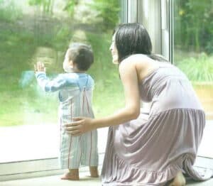 A woman and her baby looking out a window